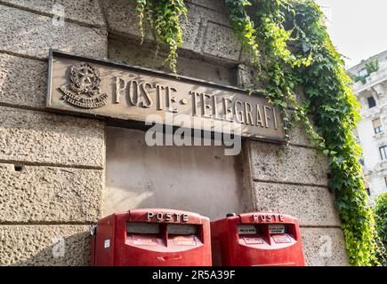 Vecchio cartello in pietra che significa "Poste e telegrafi" e due moderne caselle di posta rosse in via dell'Orso, una strada del quartiere Brera, Milano, Italia Foto Stock