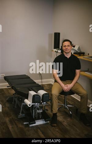 Chiropratica medico si siede su sgabello in ufficio Foto Stock