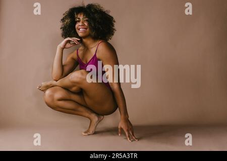 La ballerina nera femminile posa a piedi con un sorriso e capelli ricci Foto Stock