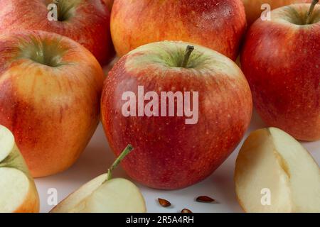Primo piano di diverse mele rosse fresche. In primo piano una mela tagliata con i semi. Foto Stock
