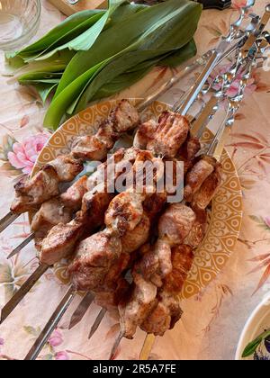 Molti succosi kebab di carne pronti su un piatto. Pezzi di carne fritti puntati su spiedini di metallo. Barbecue pronto. Cucinare in natura Foto Stock