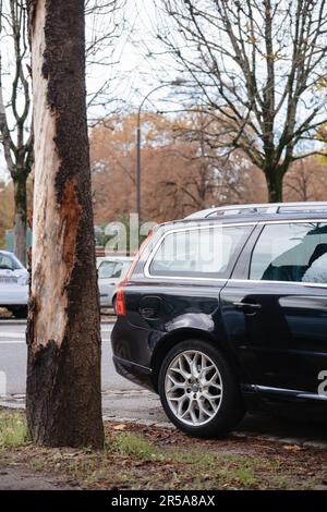 Strasburgo, Francia - 22 novembre 2022: Un'auto svedese parcheggiata in una strada cittadina accanto a un tronco di albero e impianto. Questa carrozza nera Volvo è un comodo trasporto per pendolari e passeggeri. Foto Stock