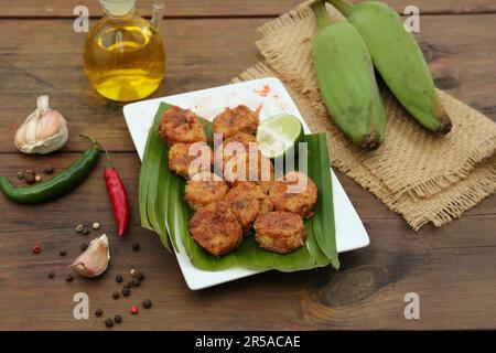 Deliziose banane fritte, frutta fresca e diversi peperoni sul tavolo di legno Foto Stock