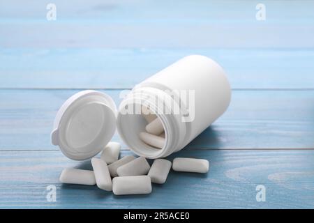 Vaso con gomme da masticare su tavolo di legno azzurro Foto Stock