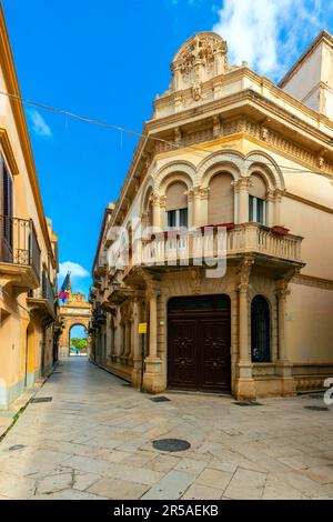 Vista su Via XI Maggio, Palazzo Spano Burgo (costruito nel XX secolo) e porta Nuova a Marsala, Sicilia, Italia. Foto Stock