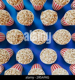 Secchi a strisce rosse e bianche pieni di popcorn. Scatole di carta piene di snack salati e deliziosi fatti di mais appena schiumato. I pacchetti sono distribuiti Foto Stock