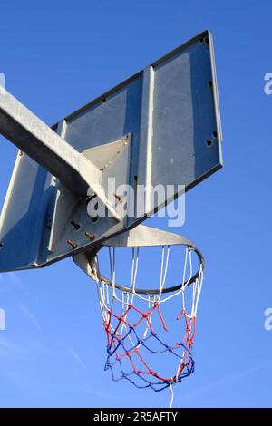 Vista ad angolo basso di un canestro da basket con una rete rotta Foto Stock