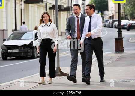 I dipendenti degli uffici camminano lungo la strada cittadina. Due uomini ridenti in suite business а e donna elegante insieme, concetto di persone di successo, partner Foto Stock