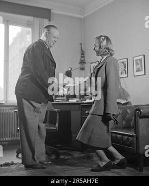 Come si fa? L'uomo tiene la mano delle donne più giovani e piega le ginocchia in una curtsy. Un modo in cui le donne salutavano principalmente gli uomini in passato. È attrice cantante Alice Babs Sjöblom. Svezia 1942. Kristoffersson rif A25-4 Foto Stock