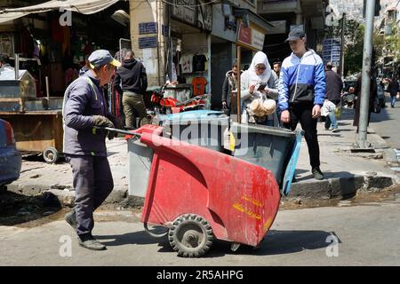 Un uomo spinge un carro spazzatura nella città di Damasco, in Siria Foto Stock