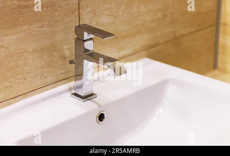 Mixer di lusso e moderno lavabo bianco in un bel bagno beige Foto Stock