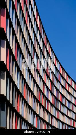 Edificio di uffici multicolore che si presenta con una facciata dal cielo blu chiaro. Foto Stock