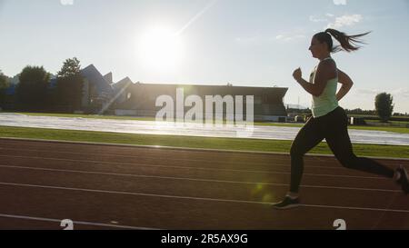 Giovane atleta caucasica, forte e muscolosa, in esecuzione su una pista atletica all'aperto, tiro medio. Foto Stock
