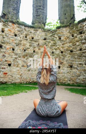 ragazza meditando nelle rovine di una vecchia chiesa e mettere una mano Foto Stock