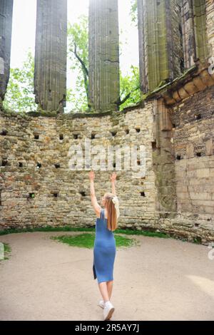 ragazza meditando nelle rovine di una vecchia chiesa e mettere una mano Foto Stock