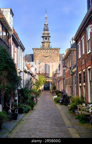 HAARLEM, PAESI BASSI - 12 APRILE 2022: Un tranquillo vicolo acciottolato (Kerkstraat) con la torre della chiesa e le case tradizionali. Foto Stock