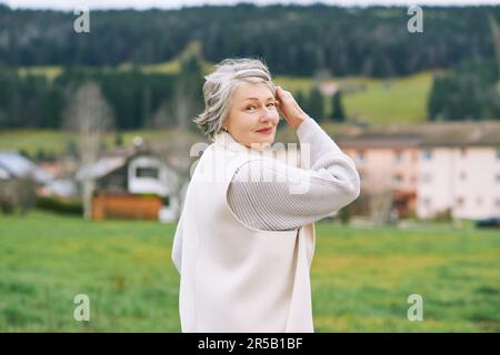 Ritratto all'aperto di bella donna di mezza età, con cappotto bianco Foto Stock