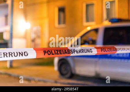 Un'auto della polizia parcheggiata accanto al nastro di polizia bianco e rosso in primo piano Foto Stock