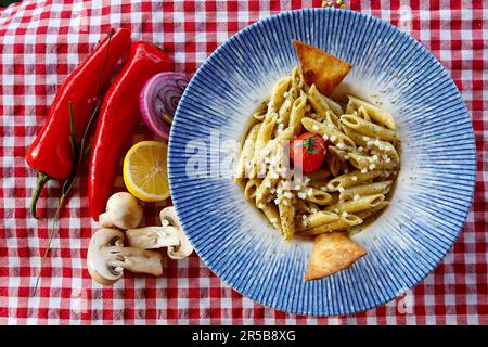 Un piatto di pasta con pesto, funghi e altre verdure Foto Stock