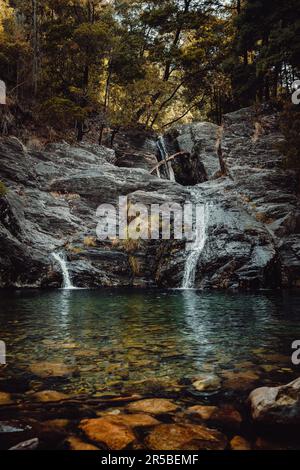 Una tranquilla scena all'aperto caratterizzata da un corpo d'acqua circondato da grandi rocce e alberi Foto Stock