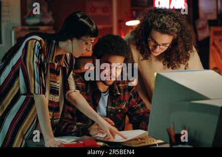 Gruppo di giovani startup che discutono insieme il progetto al tavolo di fronte al computer Foto Stock