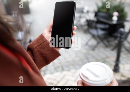 Immagine ritagliata delle mani della donna che tiene lo smartphone con una schermata vuota dello spazio di copia per il messaggio di testo o il contenuto promozionale Foto Stock