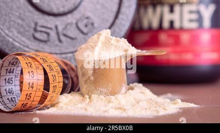 Proteina del siero di latte in paletta con 5kg dumbbel e nastro di misurazione Foto Stock