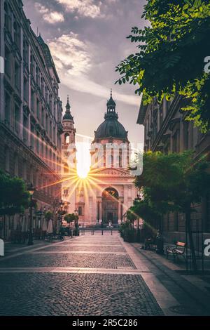 Uno scatto verticale del sole che splende attraverso le torri del St Basilica di Stefano a Budapest, Ungheria Foto Stock