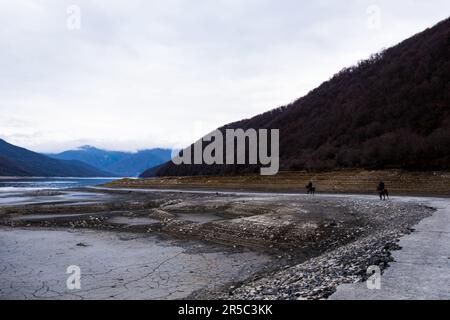 Un'immagine aerea di un lago di montagna circondato da un paesaggio invernale di cime innevate, con una superficie ghiacciata del lago che si affaccia alla luce del sole Foto Stock