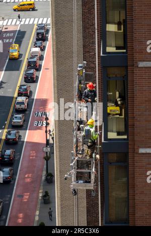 Operai edili sopra la 34th Street a New York City in una piattaforma sospesa, Midtown Manhattan, USA 2023 Foto Stock