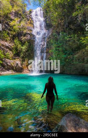 Una donna in un paesaggio pittoresco, camminando attraverso le acque basse e cristalline di un paradiso tropicale Foto Stock