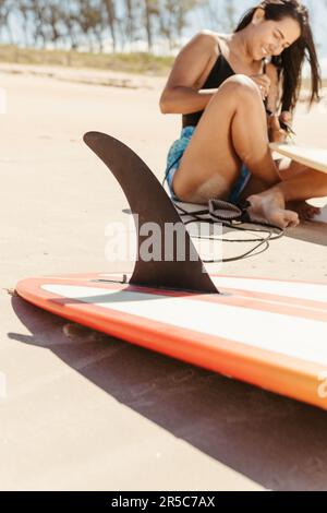 Un'atleta femminile che lavora sulla tavola da surf in mano, si prepara a colpire le onde Foto Stock