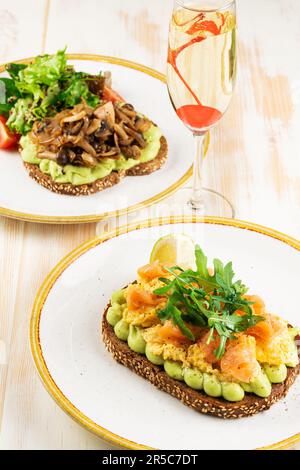 Due panini con salmone salato e funghi con un bicchiere di vino. Cibo sfondo. Foto Stock