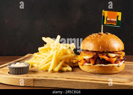 Cheeseburger fresco e gustoso con patate fritte in padella sul tavolo di legno. Concetto di fast food. Foto Stock