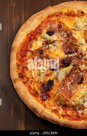 Pizza con salsa di pomodoro, selezione di formaggi misti, prosciutto, peperoni, pancetta, funghi freschi e olive su sfondo ligneo. Foto Stock