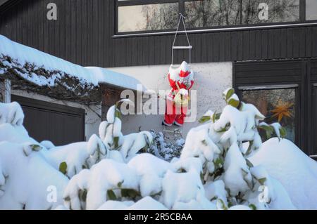 Natale artificiale del Babbo Natale con la neve che sale sulla casa Foto Stock