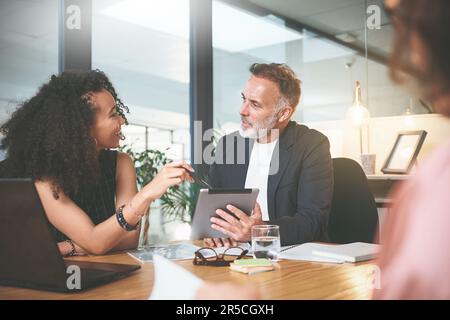 Penso che i clienti ameranno questo. due uomini d'affari seduti insieme in ufficio e che discutono mentre usano un tablet digitale. Foto Stock