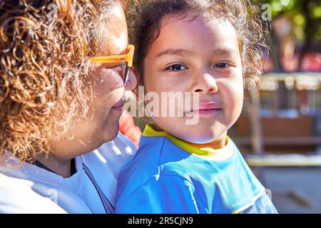 ragazza latina giocatore di calcio in una tuta sportiva con la madre in una partita di calcio elementare per bambini Foto Stock