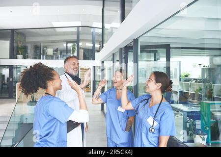 Non tutti gli angeli hanno ali, alcuni hanno stetoscopi. un gruppo eterogeneo di professionisti sanitari in piedi e si dotano reciprocamente di cinque persone. Foto Stock