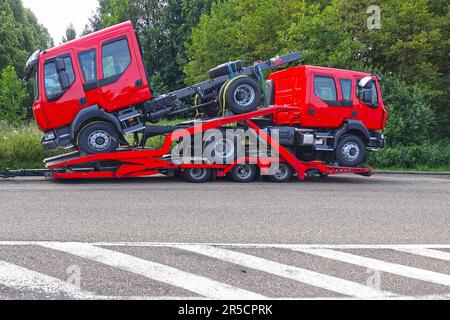 Rimorchio per trasporto di due nuovi veicoli di colore rosso. Foto Stock