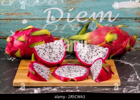 Una splendida composizione di frutti di drago su un tagliere di legno, che presenta un vibrante ed esotico mix di sapori Foto Stock
