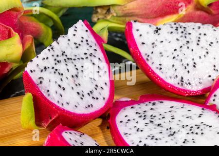 Una splendida composizione di frutti di drago su un tagliere di legno, che presenta un vibrante ed esotico mix di sapori Foto Stock
