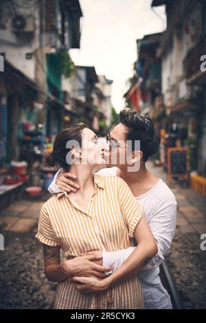 Non si possono mai avere troppi baci. Una giovane coppia che condivide un momento romantico nella città del Vietnam. Foto Stock