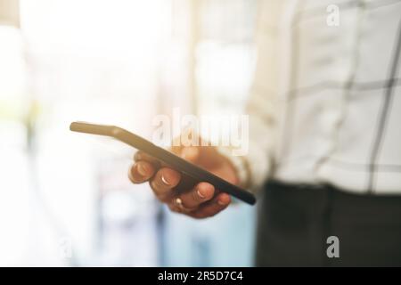 Il suo telefono è stato brulicante di messaggi in arrivo. Primo piano di una donna d'affari irriconoscibile utilizzando un cellulare in un ufficio. Foto Stock