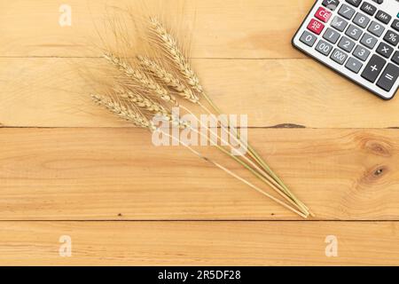 Grano raccolto con calcolatrice su sfondo di legno Foto Stock