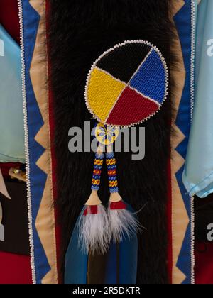 Medaglione con perline di semi gialli, rossi, blu e neri, con nappine sulla coda di un costume tradizionale da pow-wow. Foto Stock