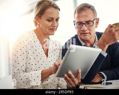 La vita domestica nell'era dell'app. una coppia matura che utilizza un tablet digitale insieme a casa. Foto Stock