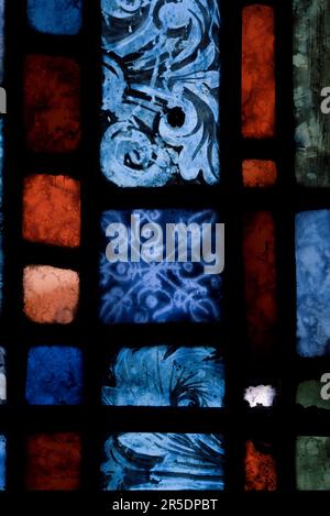 Immagine di un particolare in primo piano di vetro colorato con piombo che mostra quadrati, rettangoli di blu, rossi, verdi e dettagli dipinti. Periodo medievale. Foto Stock