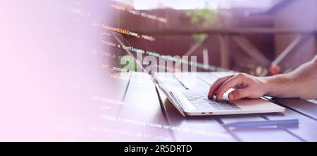 Uomo che lavora su un computer portatile in giardino. Primo piano delle mani maschili che scrivono sul computer Foto Stock