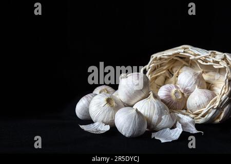 Spicchio fresco Garlics o aglio perla o solo aglio, varietà di Allium ampeloprasum con cestino isolato su sfondo nero Foto Stock